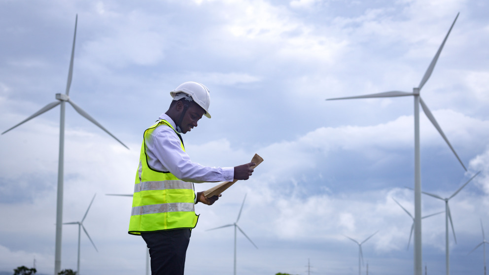 African engineer standing in front of wind turbine