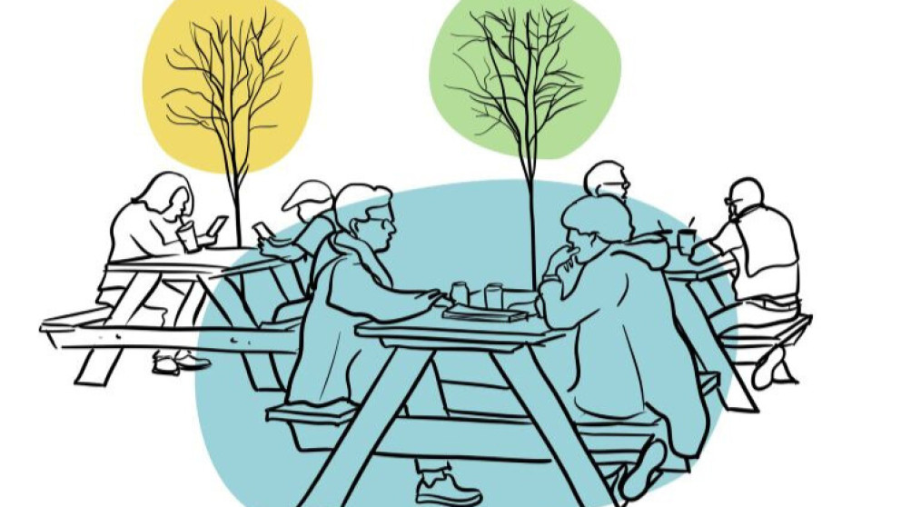 People sitting at picnic tables in a park