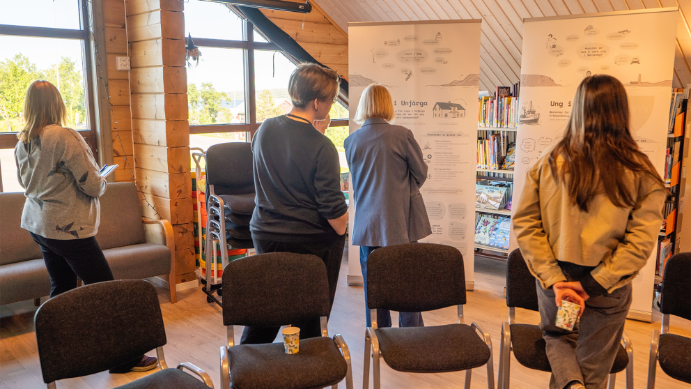 Visitors engaging with a roll-up poster at the sharing exhibition.