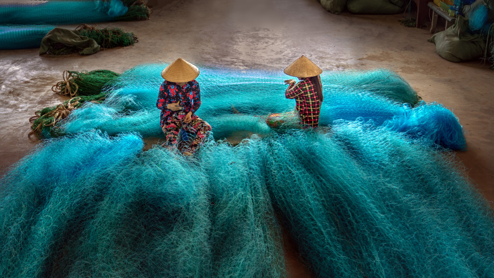 Vietnamesinnen reparieren Fischernetze in einer Reparaturwerkstatt. Obwohl Frauen alle Arten von Tätigkeiten erledigen, die mit dem Ozean zusammenhängen, ist die Ungleichbehandlung der Geschlechter verbreitet.