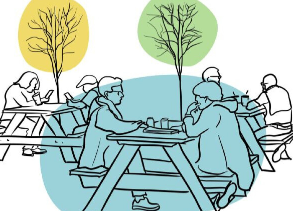 People sitting at picnic tables in a park