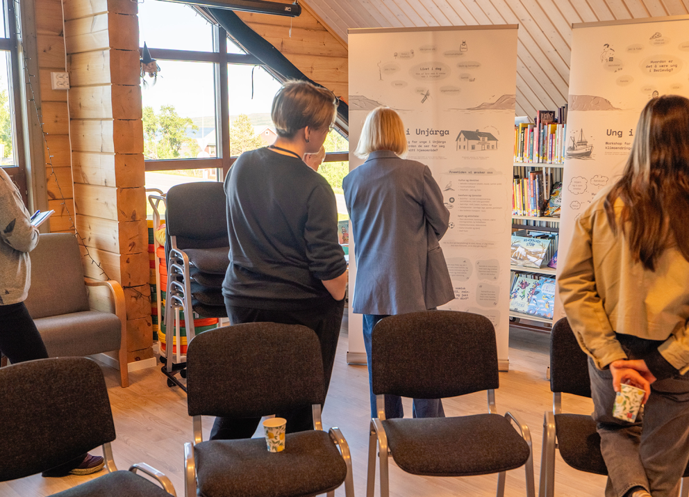 Visitors engaging with a roll-up poster at the sharing exhibition.