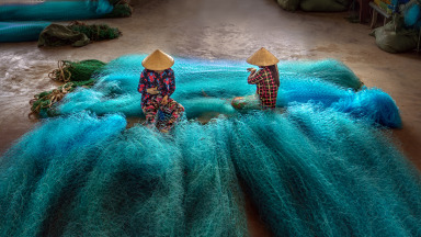 Vietnamesinnen reparieren Fischernetze in einer Reparaturwerkstatt. Obwohl Frauen alle Arten von Tätigkeiten erledigen, die mit dem Ozean zusammenhängen, ist die Ungleichbehandlung der Geschlechter verbreitet.