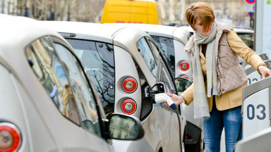 Eine Frau lädt in Paris ein Elektroauto auf.